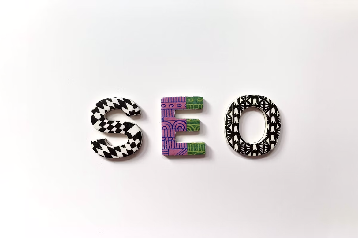 Lettere decorative che formano la parola "SEO" su sfondo bianco, ciascuna con motivi grafici e colori diversi.
